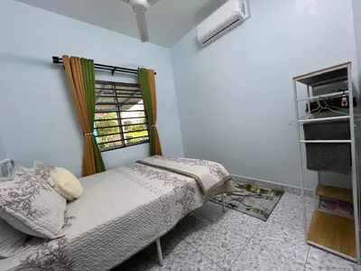 a bedroom with a bed and a window at Leman's Homestay in Balik Pulau