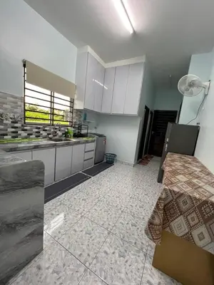 a large kitchen with white cabinets and a table at Leman's Homestay in Balik Pulau