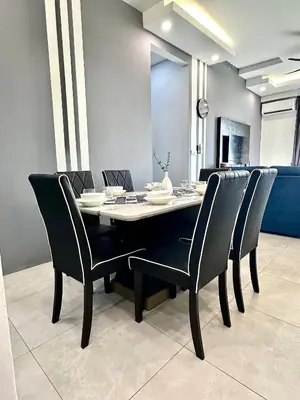 a dining room table with black chairs and a clock at Aston Acacia Residence Bukit Mertajam in Bukit Mertajam