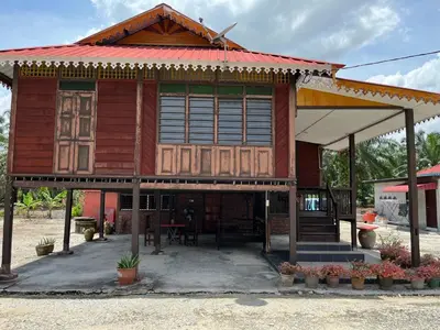 a wooden house with a red roof at Homestay wak saripan Rumah Kayu in Teluk Intan