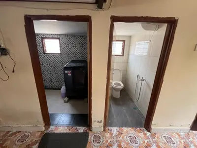 a bathroom with a toilet and a door leading to a bathroom with a sink at Homestay wak saripan Rumah Kayu in Teluk Intan