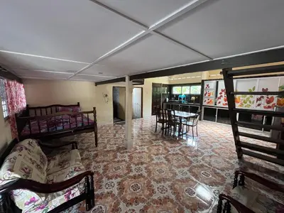 a living room with a couch and a table and chairs at Homestay wak saripan Rumah Kayu in Teluk Intan