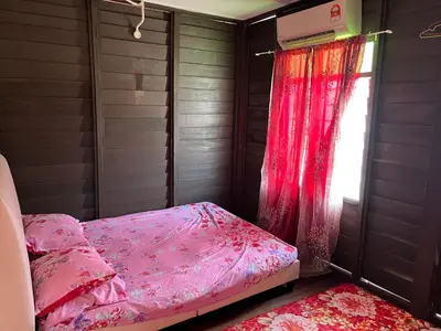 a bedroom with a pink bed and a window at Homestay wak saripan Rumah Kayu in Teluk Intan