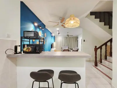 a living room with two stools and a counter with a tv at Ipoh pasir puteh vibrant home 4br 15 pax in Ipoh