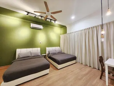 a bedroom with two beds and a green wall at Ipoh pasir puteh vibrant home 4br 15 pax in Ipoh