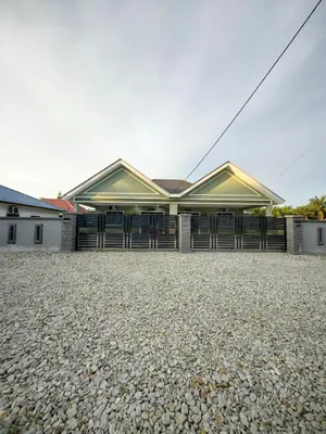 a building with a lot of doors on a gravel driveway at Homestay Segari in Lumut