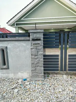 a building with a garage door with a stone pillar at Homestay Segari in Lumut
