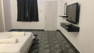 a room with a bed and a tv and a door at Capital O 91205 Palong Hill Chalet & Resort in Baling