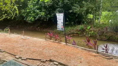 a sign in front of a pond in a garden at Capital O 91205 Palong Hill Chalet & Resort in Baling
