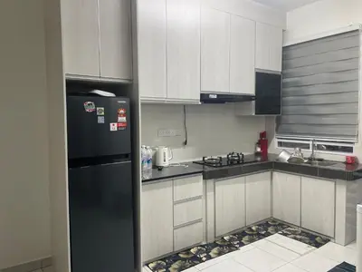 a kitchen with white cabinets and a black refrigerator at Homestay Cikgu Ina in Kampong Chepor