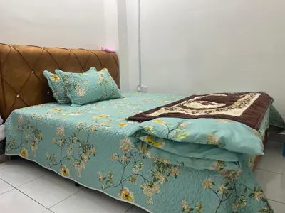 a bed with a blue comforter and pillows at Homestay Cikgu Ina in Kampong Chepor
