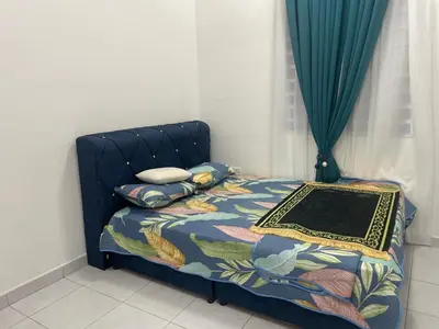 a bedroom with a bed with a blue bedspread and pillows at Homestay Cikgu Ina in Kampong Chepor