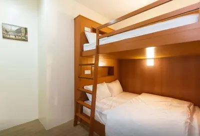 a bedroom with two bunk beds with white sheets at Penang Hill Lodge in Ayer Itam