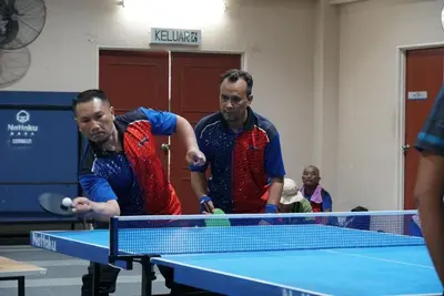 two men playing a game of table tennis at Railway Hostel in Batu Gajah