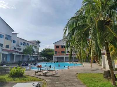a swimming pool with a palm tree and people in it at Pangkor Lot10 Vacation Studio in Pangkor