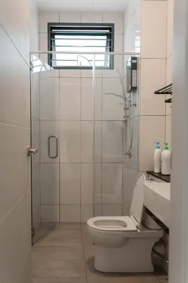 a bathroom with a toilet and a glass shower at SpaciousFun4BR Home 9Pax 3Bath Snooker ALMA in Bukit Mertajam