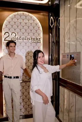 a man and a woman taking a picture in front of a machine at 22 Macalisterz George Town By Mana-Mana in George Town