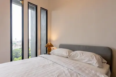a bedroom with a bed with white sheets and windows at Beacon Executive Service Suite Penang in George Town