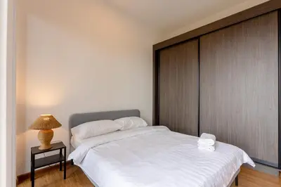 a bedroom with a white bed with a wooden headboard at Beacon Executive Service Suite Penang in George Town
