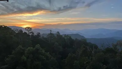 a sunset in the mountains with trees in the foreground at A357 Silverpark Resort Best Mountain view in Bukit Fraser