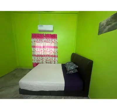 a green room with a bed in front of a window at Capital O 91206 Homestay Pelangi Ban Pecah. (muslim Only)