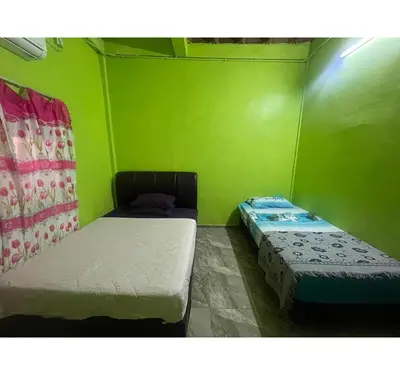 two beds in a room with green walls at Capital O 91206 Homestay Pelangi Ban Pecah. (muslim Only)