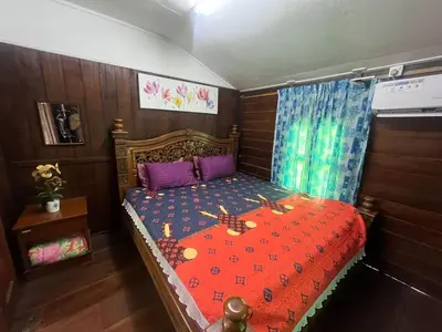 a bedroom with a bed with a red comforter at Capital O 91206 Homestay Pelangi Ban Pecah. (muslim Only)
