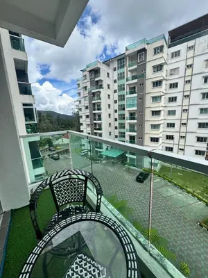 a balcony with two chairs and a table and some buildings at AYAAN Luxe Premium FIFA house with Free WiFi and Netflix in Tanah Rata