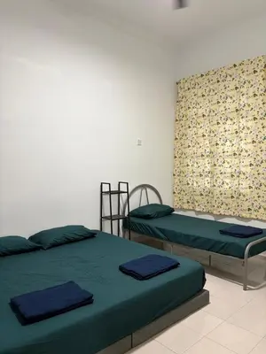 two twin beds in a room with a curtain at Bidor Homestay in Bidur