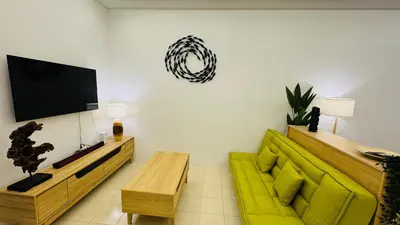 a living room with a green couch and a flat screen tv at 122 SEGARi in Lumut