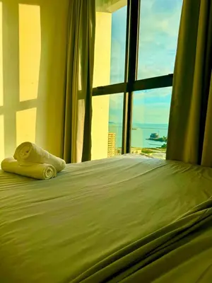 a bed with a towel laying on it in front of a window at Luxury 3BR Seaview Getaway Perfect for 10 Guests A29 in George Town