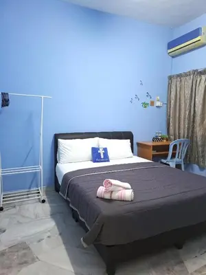 a bedroom with a bed with a blue wall at Acacia Guesthouse by ZamanJa in Ipoh