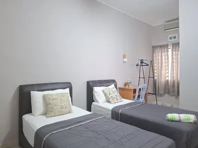 a bedroom with two beds and a table and a chair at Acacia Guesthouse by ZamanJa in Ipoh