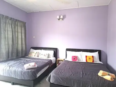 two beds in a room with purple walls at Acacia Guesthouse by ZamanJa in Ipoh