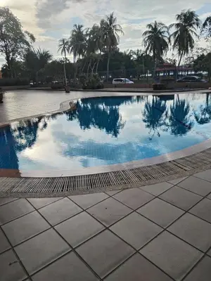 a swimming pool with palm trees in the background at Ed 03 lumut Waterfront in Lumut