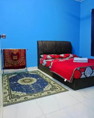 a bedroom with a bed with a red blanket and a blue wall at The Batrisyia Homestay in TanjongMalim