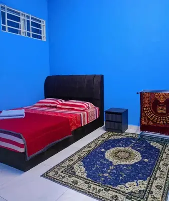 a bedroom with a bed and a blue wall at The Batrisyia Homestay in TanjongMalim