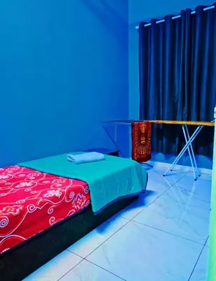 a room with a bed and a table with blue lights at The Batrisyia Homestay in TanjongMalim