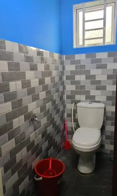 a bathroom with a toilet and a red bucket at The Batrisyia Homestay in TanjongMalim