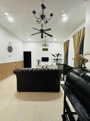 a living room with a leather couch and a chandelier at Madam Cottage Homestay in Sungai Petani