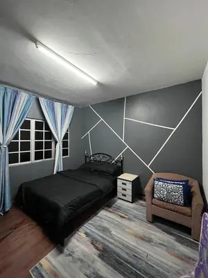 a bedroom with a black bed and a chair at Dheaa's Homestay Cameron Highlands in Tanah Rata