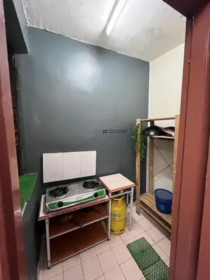 a small kitchen with a stove and a blue wall at Dheaa's Homestay Cameron Highlands in Tanah Rata