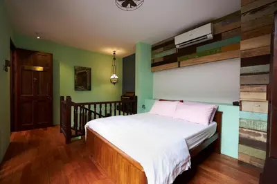 a bedroom with a bed with wooden floors and green walls at You Le Yuen in George Town