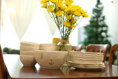 a table with plates and a vase with yellow flowers at Comfy Sofy-Bunny Vintage Penthouse in Tanah Rata