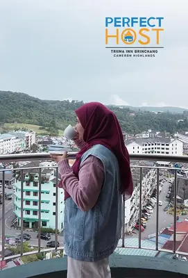 a woman drinking a cup of coffee on a balcony at Triima Inn Brinchang by Perfect Host in Brinchang