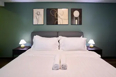 a bedroom with a bed with white sheets and two lamps at Maritime Suite with Seaview 2BR - Water Dispenser - Dryer in George Town