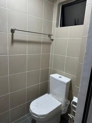 a bathroom with a white toilet and a mirror at The Cozy Loft in Kampar