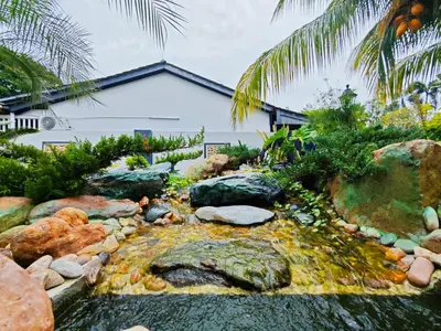 a garden with a pond in front of a house at DAWA Brickhouse - Balinese Guesthouse in Thompson Ipoh by Ryokan Management in Ipoh