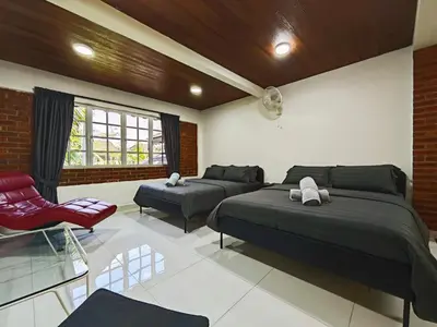 a bedroom with two beds and a red chair at DAWA Brickhouse - Balinese Guesthouse in Thompson Ipoh by Ryokan Management in Ipoh