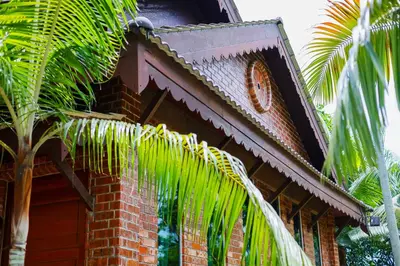 a clock on the side of a building with a palm tree at DAWA Brickhouse - Balinese Guesthouse in Thompson Ipoh by Ryokan Management in Ipoh
